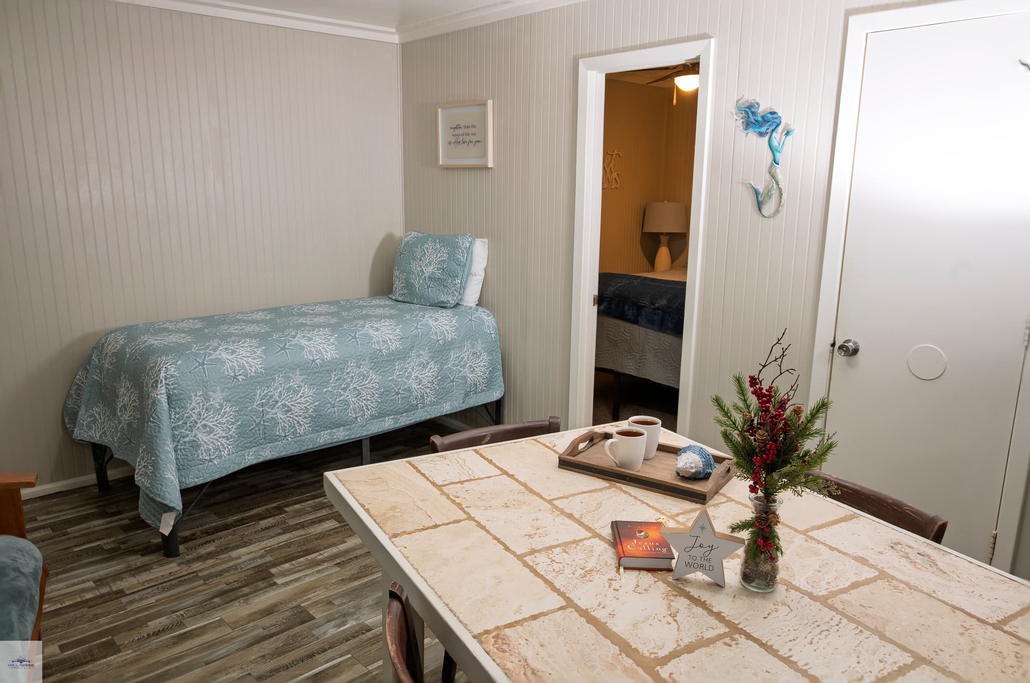 A bedroom with a twin bed, dining table, and a doorway open to another bedroom