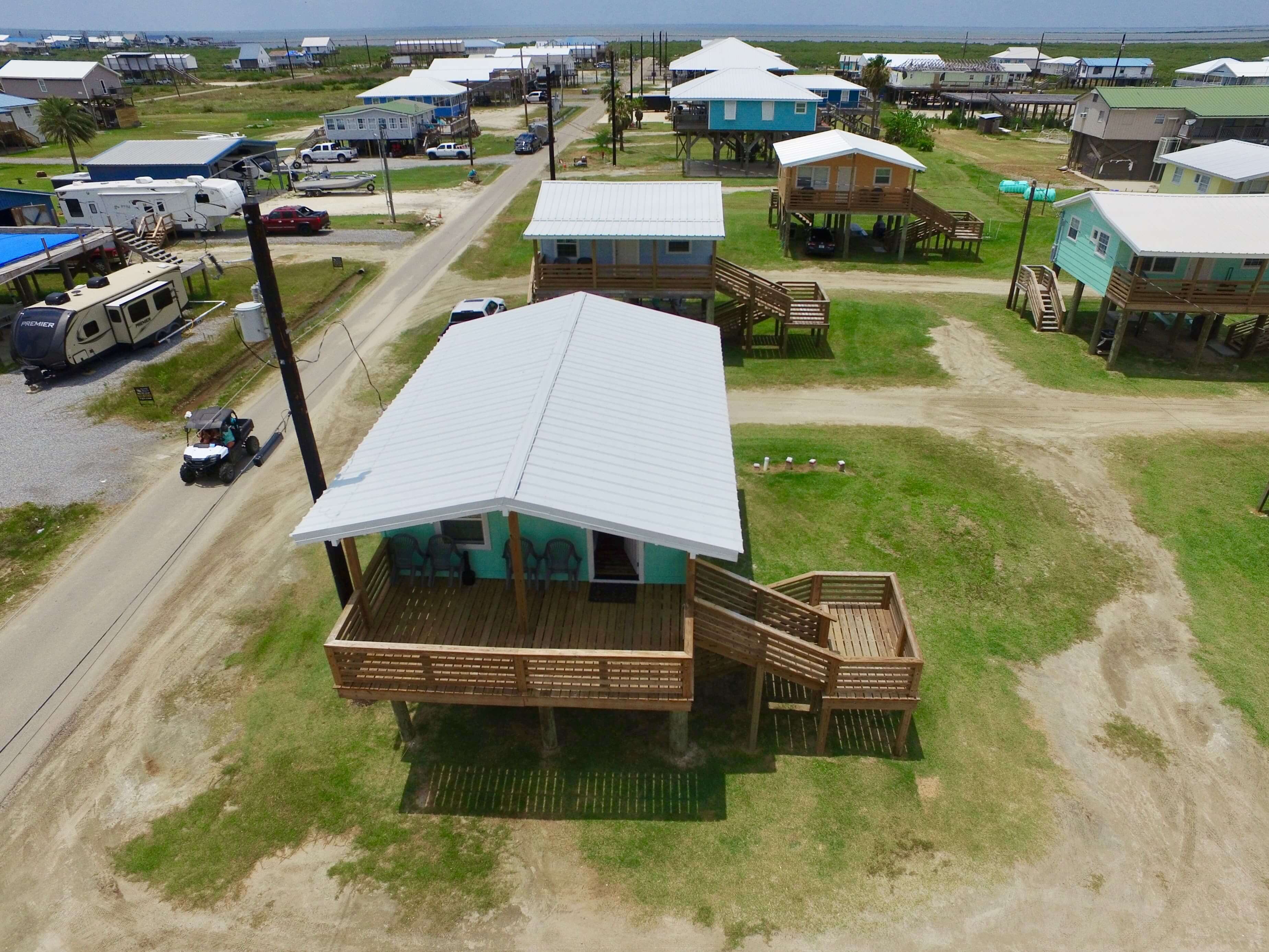Aerial view of a coastal neighborhood with colorful houses and a dirt road.