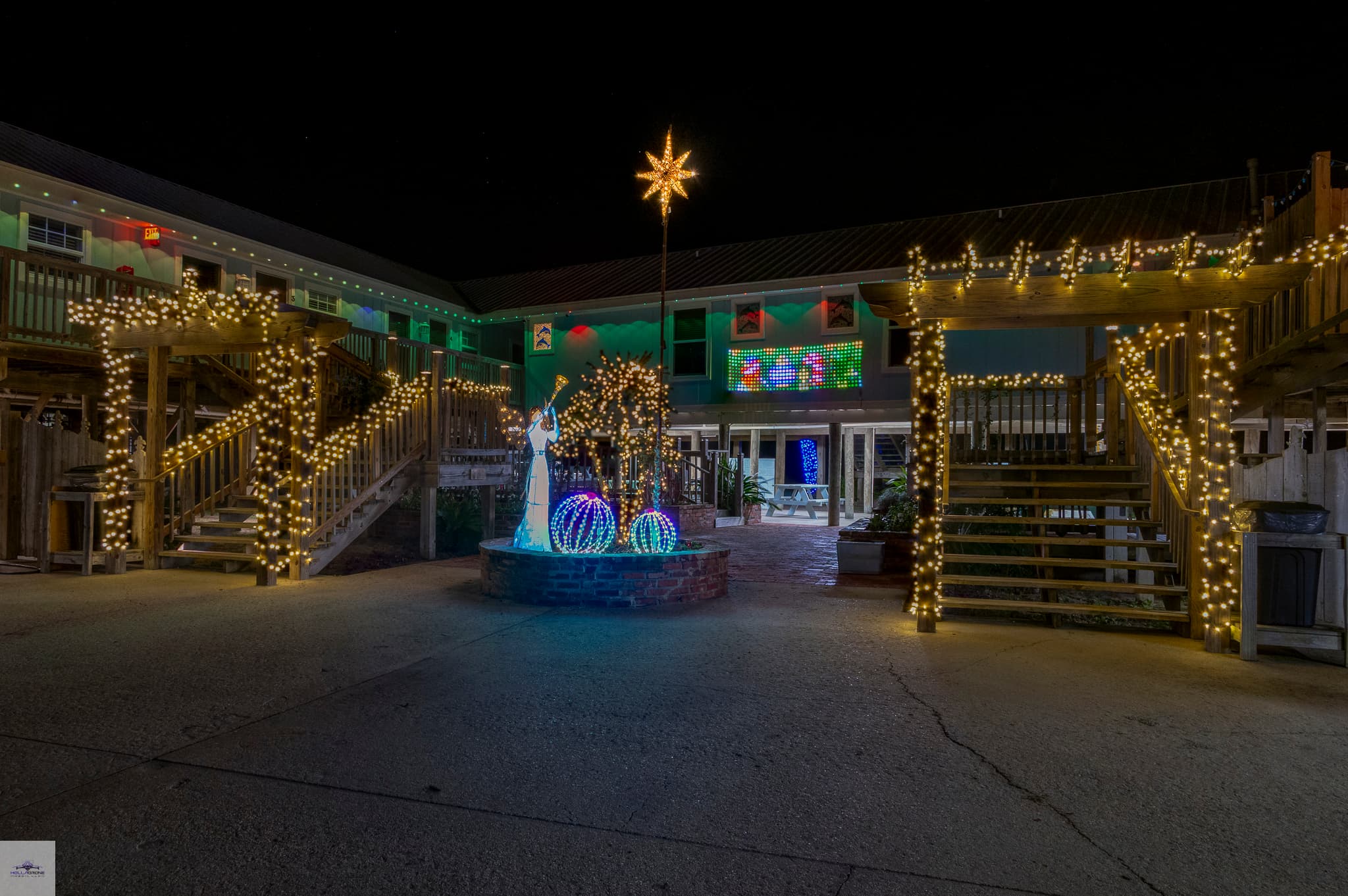A festive courtyard illuminated with holiday lights and decorations at night. A festive courtyard illuminated with holiday lights and decorations at night.